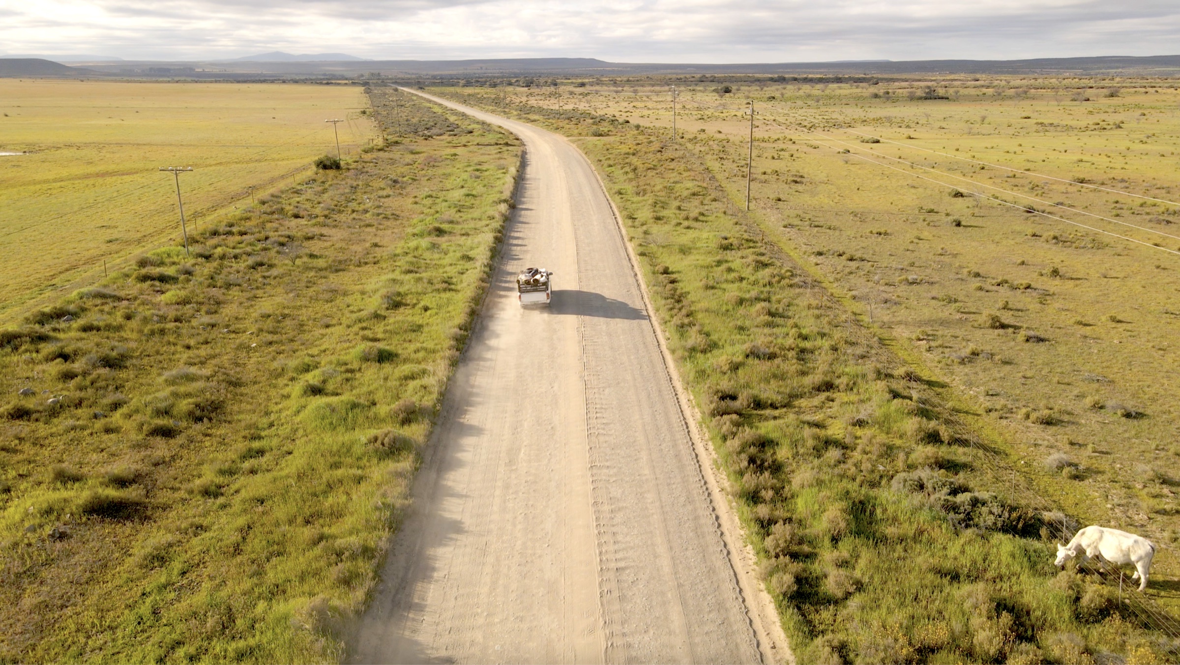 Aerial drone view of a bakkie on a dirt road through Namakwaland farmland